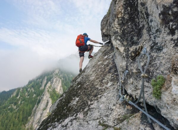 A stunning shot of a young man climbing up a cliff on a cold and foggy day