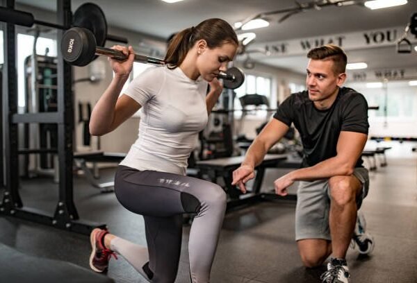 Fitness Instructor Guiding Young Woman When She Exercises.